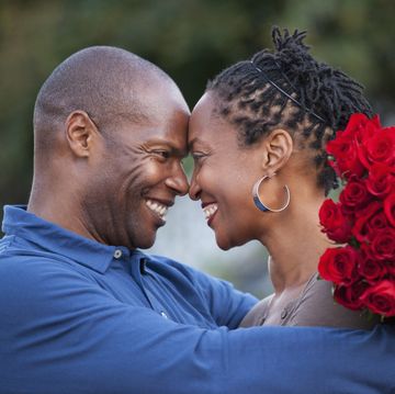 man hugging wife and giving her red roses