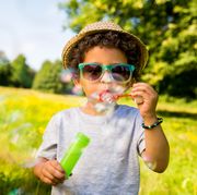 child blowing bubbles in park