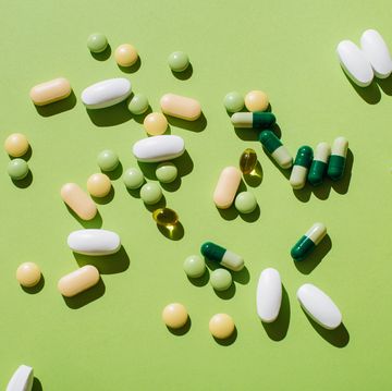 colorful pills and capsules on green background minimal medical concept flat lay, top view