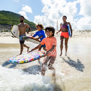 family running and splashing into sea together with body boards