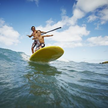 Father and son riding wave on stand up paddleboard father and son riding wave on stand up paddleboard