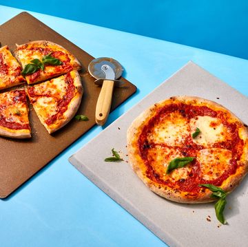 two pizza stones with two pizzas on top, one that is cut