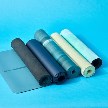 five rolled up yoga mats on a blue set, good housekeeping's best yoga mats