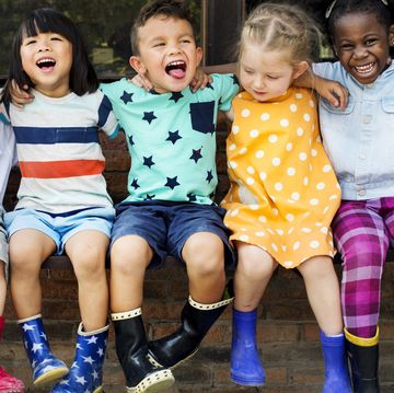 group of kindergarten kids friends arm around sitting and smiling fun