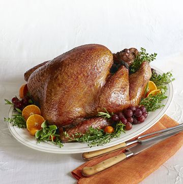 golden roasted turkey on a serving platter with grapes, orange slices, and herbs