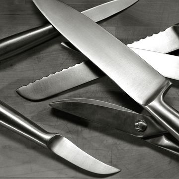 set of stainless steel knives arranged on wooden cutting board