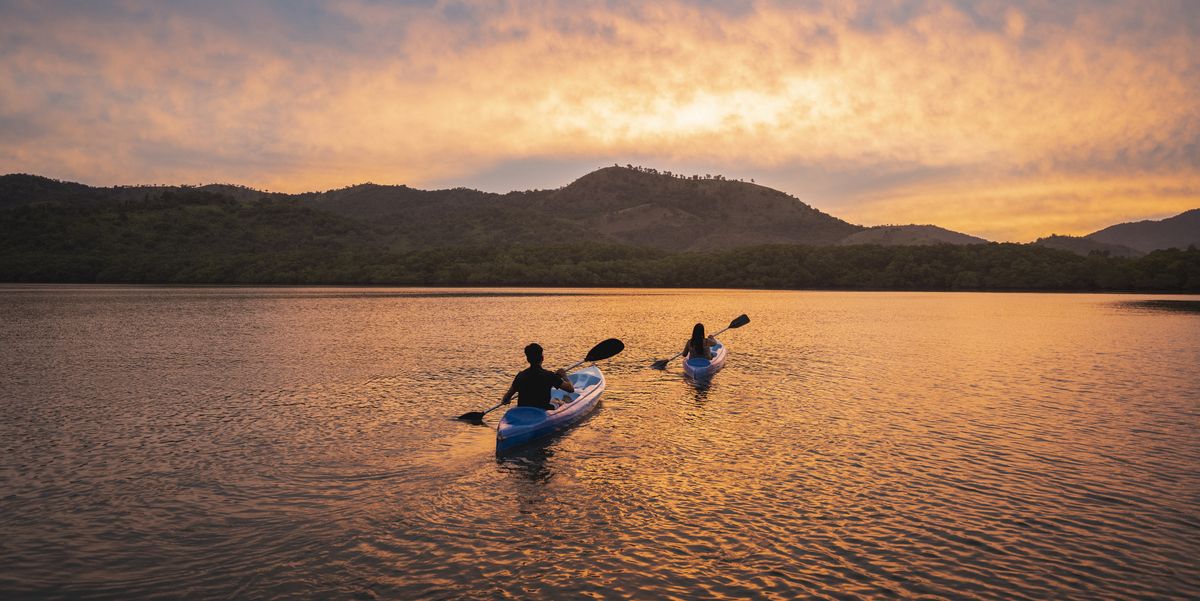 Two people kayaking in a lagoon at sunset two people kayaking in a lagoon at sunset