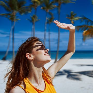 woman covers her face from the sun with her hand on the beach
