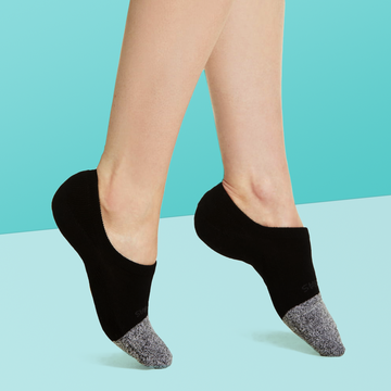 no show socks person wearing a black and grey pair of no show socks on a light blue background, good housekeeping best no show socks